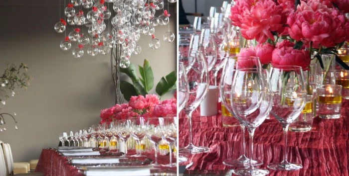 pink peonies and multiple wine glasses, on a table set for a festive meal, with a dark pink tablecloth, and multiple crystal baubles, with pink bows hanging overhead