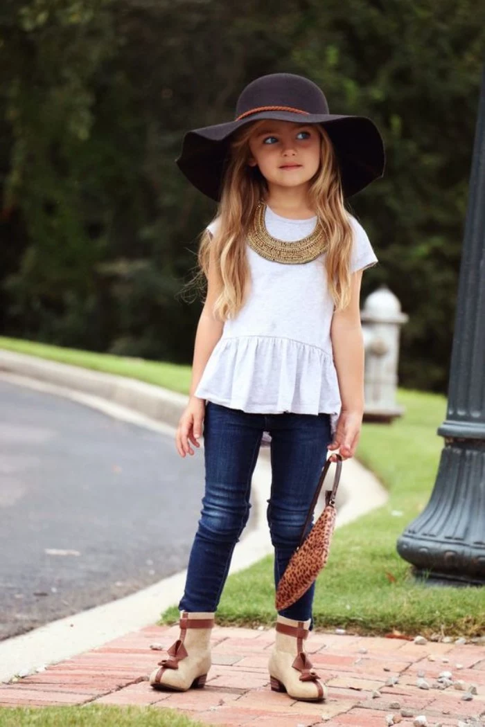 wide-brimmed black felt hat, worn by a child, with long wavy blonde hair, white peplum top, and blue skinny jeans, girls thanksgiving outfit, beige and brown ankle boots