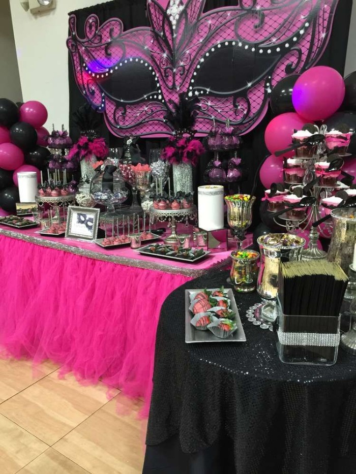 hot pink and black tables and decorations, for a masked ball-themed party, 50th birthday colors, pink balloons and a large, mask-shaped wall decoration, in black and pink