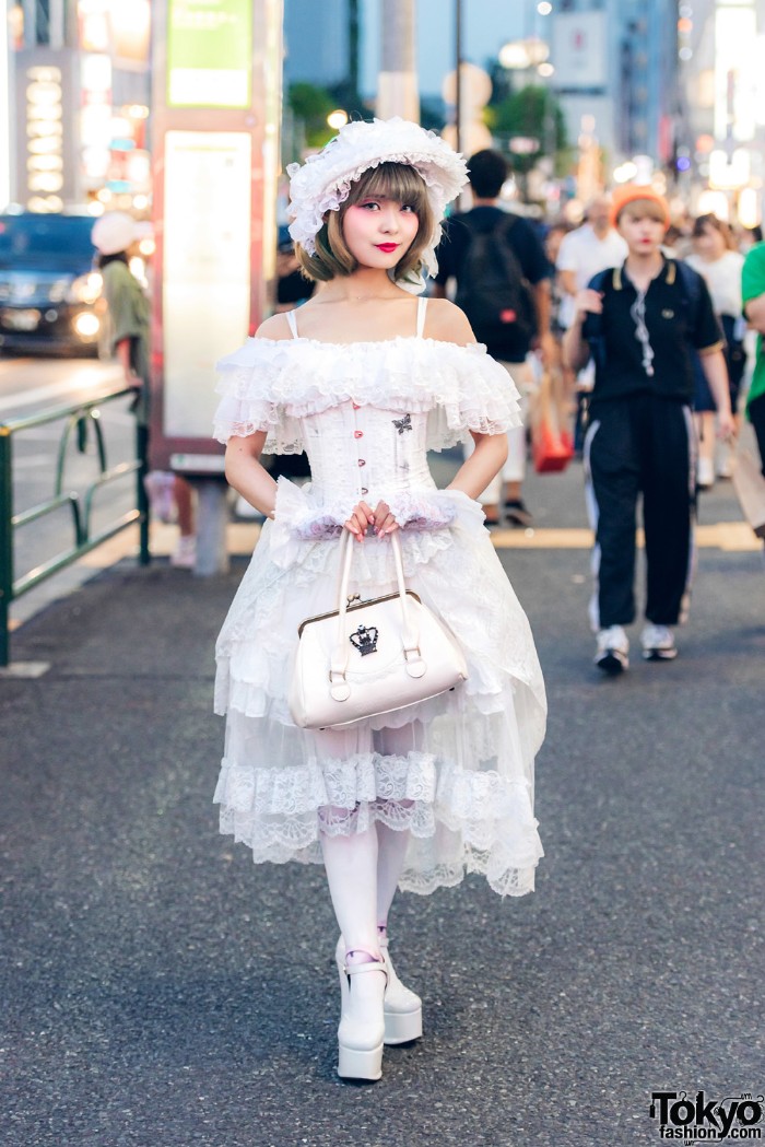 bonnet in white, with lacy frills, worn by a japanese lolita, in a tiered, off-the-shoulder white lace dress