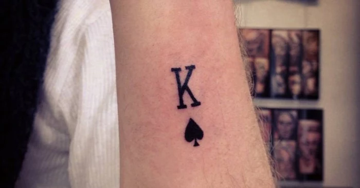 king of spades symbol, tattooed in black ink, on the arm of a man, lower arm tattoos, seen in close up