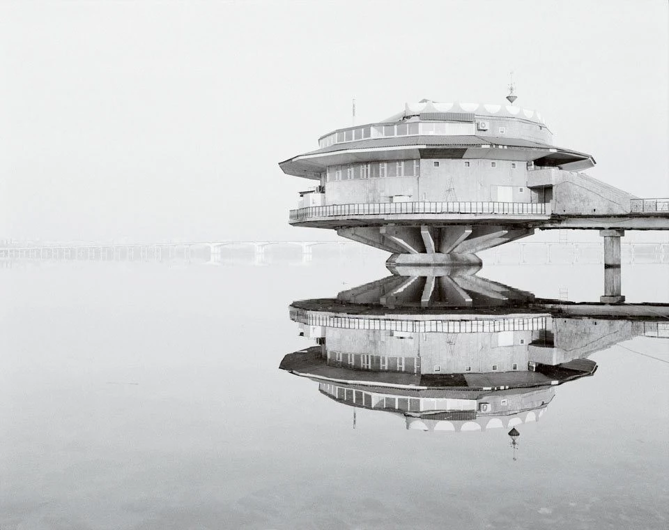 round concrete building, suspended over a lake, poplavok cafe in ukraine, brutalist architecture, seen on a black and white photo