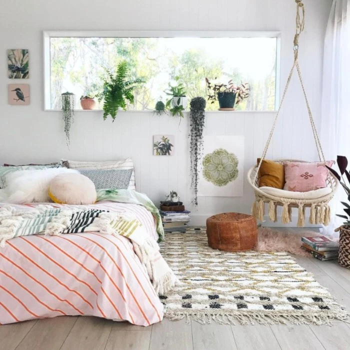 boho style room, with a woven, pale beige swing, and a bed in pastel colors, cute teen rooms, potted plants and a patterned rug, in white and beige and black
