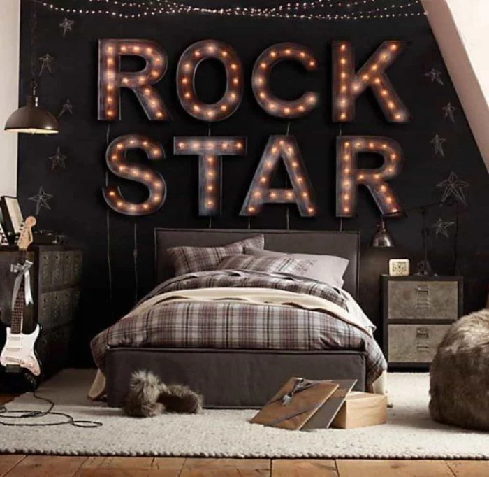 plaid brown and grey bedding, on a bed with two pillows, inside a room, with white and black walls, decorated with large illuminated letters, spelling the words rock star, cool beds for teens, pale grey carpet