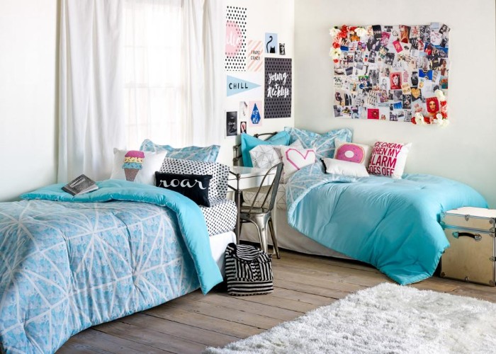 beds with blue duvets, and colorful cushions, in a room with white walls, and a wooden floor, cute teen rooms, posters and a board with photos