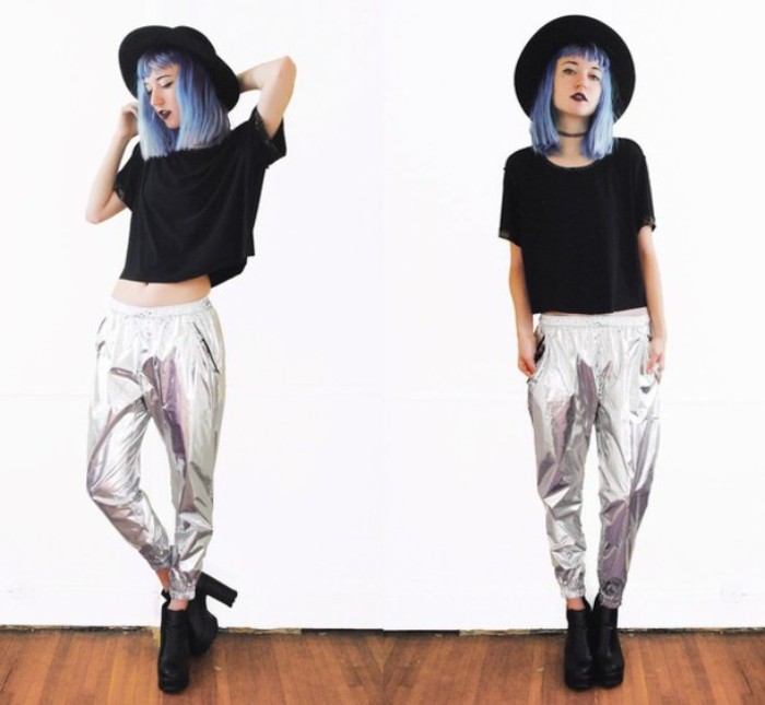 metallic trousers in silver, worn with a black cropped t-shirt, and high-heeled black leather ankle boots, 80s grunge attire, on a young woman, with light blue hair, and a black felt hat