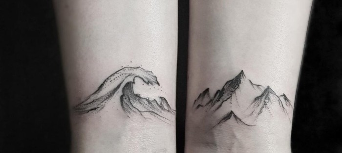 two arms with a tatto near each wrist, an ocean wave, and a mountain, small tattoos for men, done in black ink