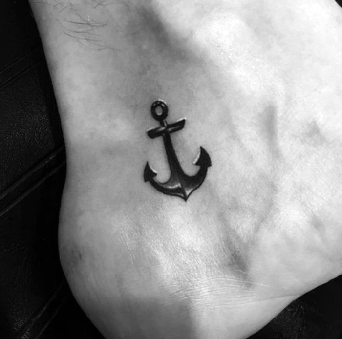 another version of an anchor tattoo, in black with white details, small symbolic tattoos, steadfastness and family, on a man's foot, close to his ankle and sole, deep meaning tattoos for guys