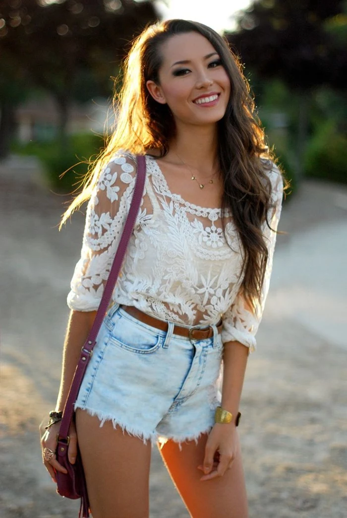 young brunette woman, dressed in pale blue denim cutoff shorts, a white bralette, and a white, see-through embroidered top, how to wear a bralette, small purple shoulder bag