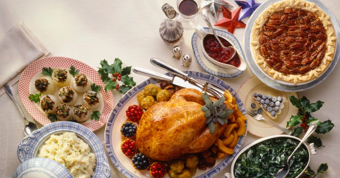 happy thanksgiving wishes, a table with several dishes, a roasted turkey, devilled eggs and mashed potato, spinach salad and pie