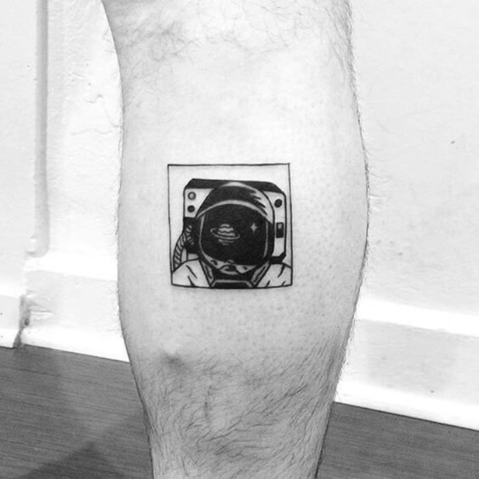 vintage austronaut's head, with a helmet, tattooed in black ink, inside a square, on a person's lower leg, small tattoos with meaning, black and white image