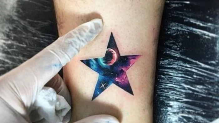 star shape containing a drawing of a starry sky, with a planet, and some purple and light blue nebulae, tattoed on a person's arm, forearm tattoos 