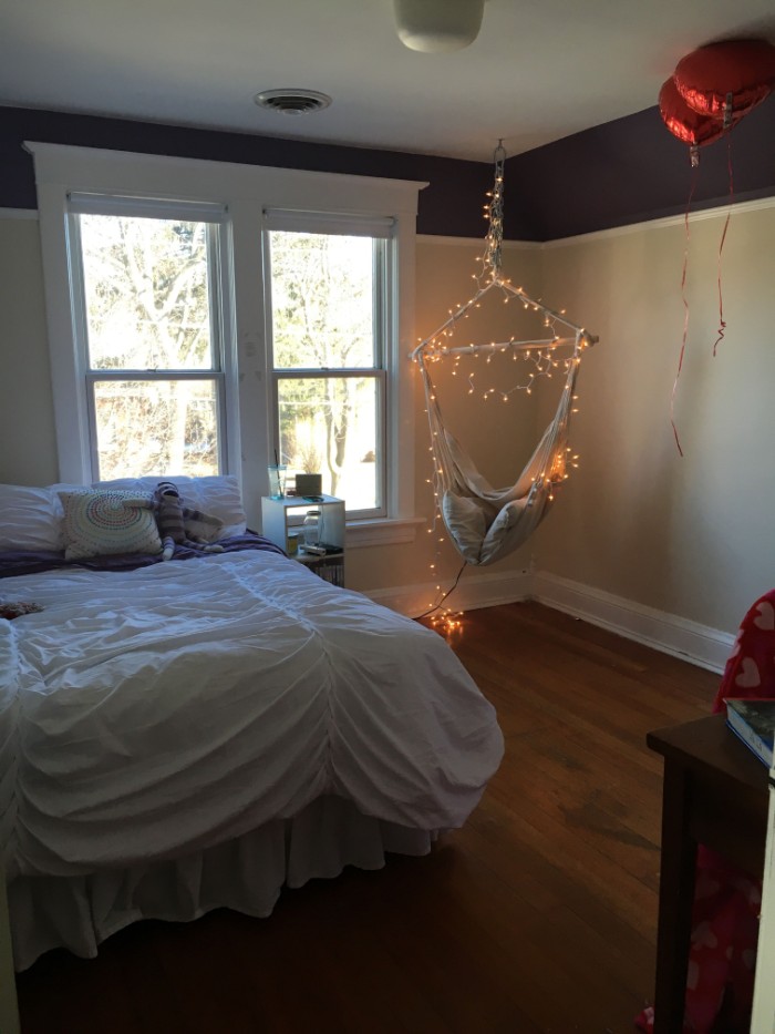 window with white frames, in a room with a bed, and a swing, decorated with lit string lights