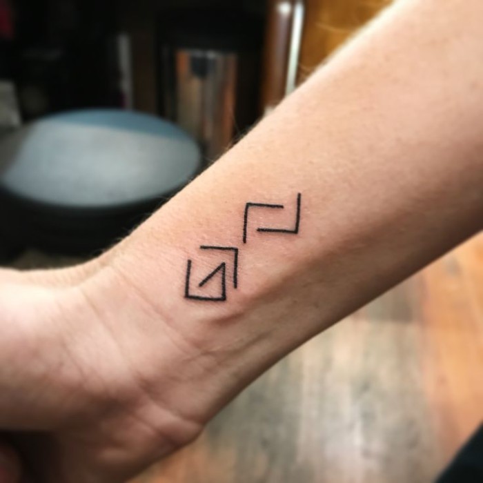 unique symbols resembling letters, tattooed in black, on a man's wrist, small symbolic tattoos, with minimalistic designs