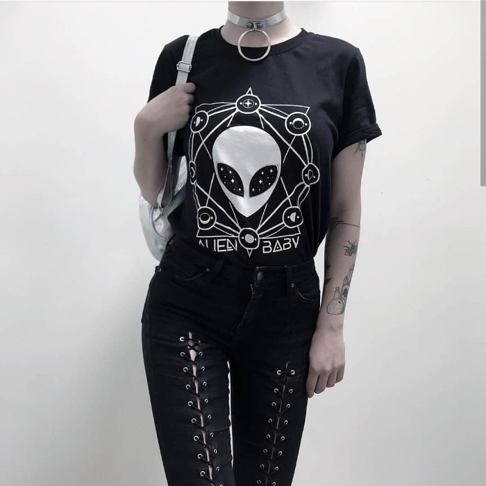 skinny jeans in black, with lace-up details, combined with a black t-shirt, featuring an alien-themed print in white, silver chocker necklace, and a silver backpack