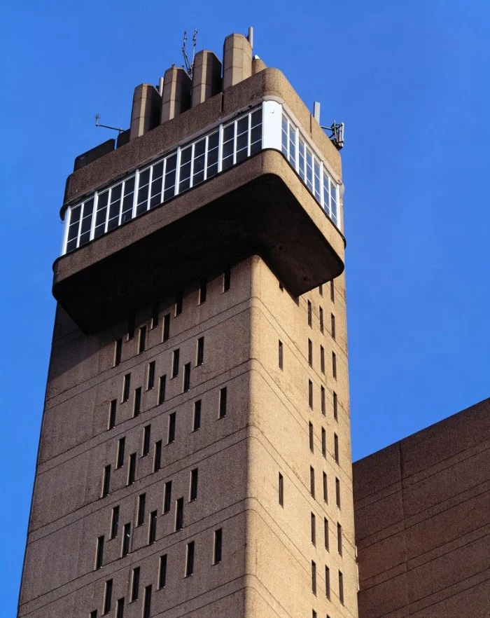 trellick tower in london england, tall structure in pale beige, with multiple narrow rectangular windows, and a balcony-like structure, concrete architecture