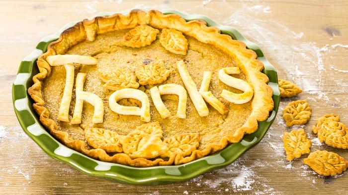 pie decorated with leaves made of dough, and the word thanks, in a green and white ornamental dish, thanksgiving messages for friends