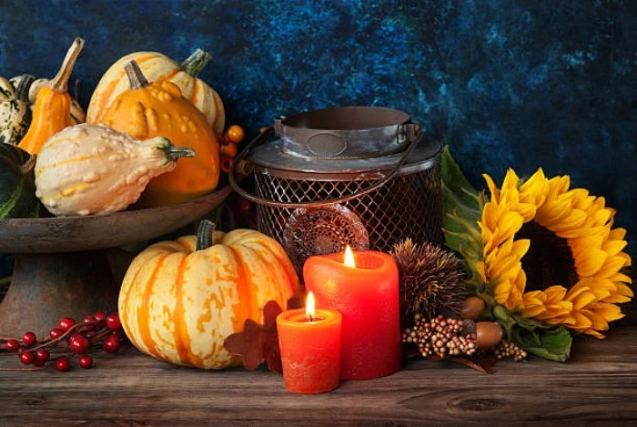 thanksgiving card messages, old metal lantern, near two lit candles, a sunflower and a selection of small pumpkins and gourds