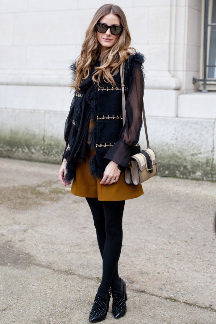 mustard yellow shorts, worn with black opaque tights, a sheer black blouse, and a black fur trimmed gilet, thanksgiving outfits