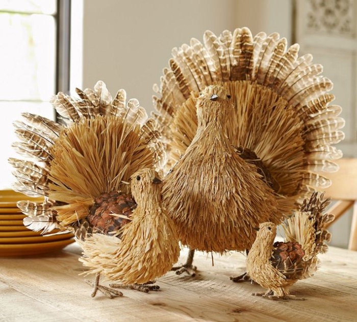 large medium and small turkey decorations, made from wicker, wood and and real turkey feathers, placed on a pale beige wooden table