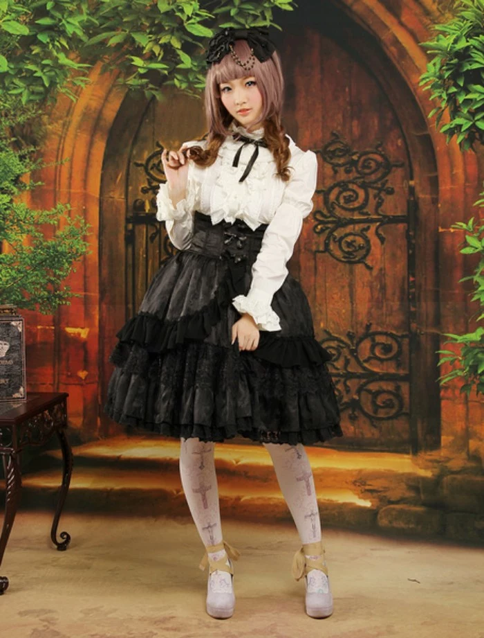 mural of an antique wooden door, behind a girl, dressed in a black and white lolita outfit, blouse with a frilly bib detail, and a black ribbon, tiered skirt with flounces