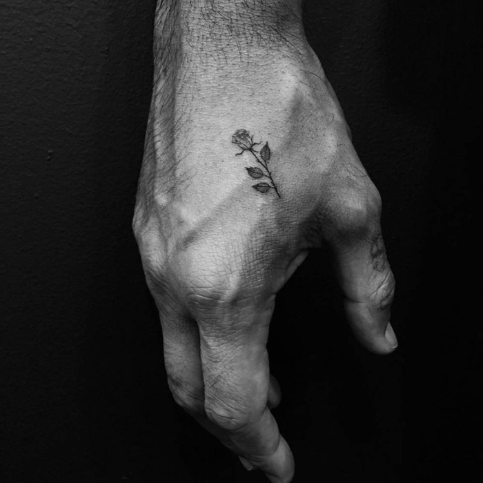 rose with four leaves, very small in size, tattooed in black, on a hand, small tattoos for men, near the thumb