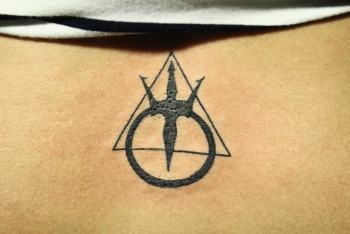 poseidon's trident with a circle, and a triangle, tattooed in black ink, meaningful tattoo ideas, seen in close up, on a person's back