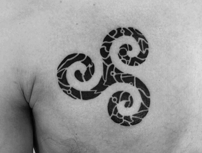 life and rebirth, symbolized by a triskele tattoo, done in black ink, with white details, small tattoos with meaning, above a man's chest