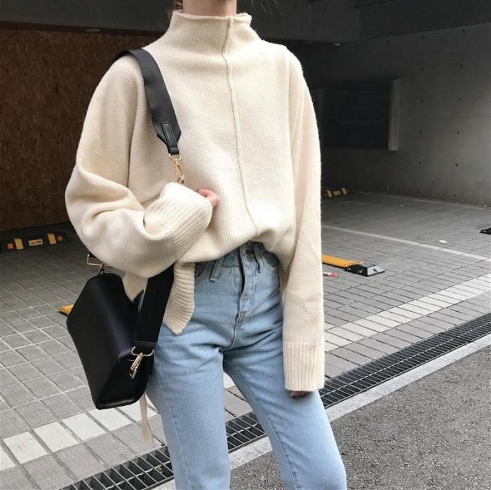 cream turttle neck jumper, oversized and featuring a rim detail, running down its front, worn half tucked in pale blue, high waisted jeans, with a black leather shoulder bag, grunge definition