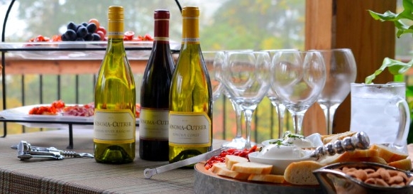 red and white wine bottles, near several plates, featuring assorted canapes, 50th birthday party ideas, clear wine glasses and fruit