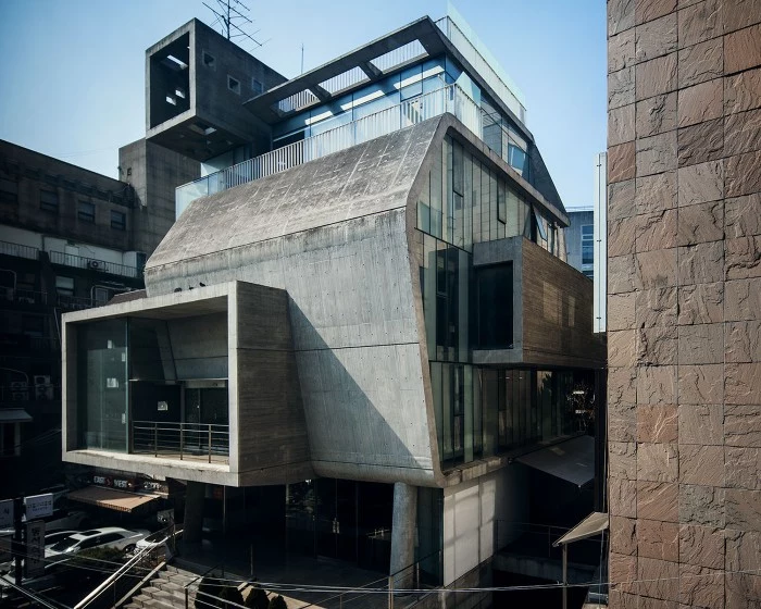 angular building made of grey concrete, with rectangular elements, and multiple windows, brutalist architecture in asia