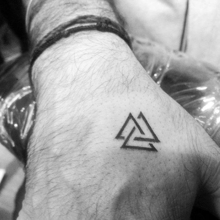 intersecting triangles in black, tattooed on a man's hand, valknut nordic symbol, associated with the god odin, cool small tattoos for guys