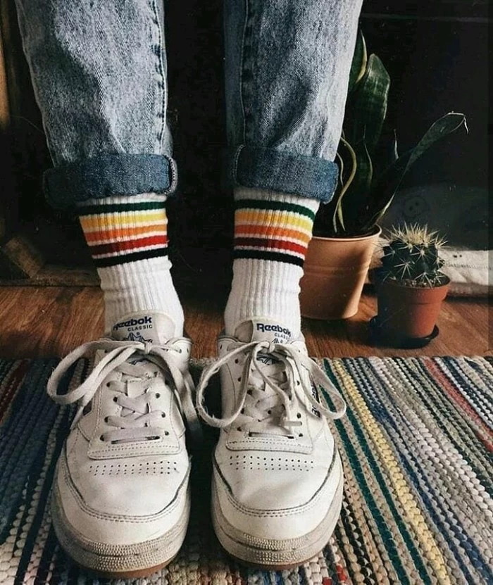 well-worn white, retro lace-up sneakers, worn with tennis socks, featuring multicolored stripes, 90s grunge items, acid wash ankle jeans