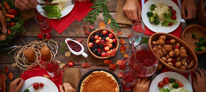 table set for four, white plates filled with vegetables, jug of red juice and glasses, walnuts and berries in wooden bowls, thanksgiving messages for friends, rustic table decor