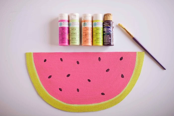 five bottles of paint, and a used paint brush, placed near a piece of cork, painted to look like a slice of watermelon, cheap ways to decorate a teenage girl's bedroom, customized bulletin board