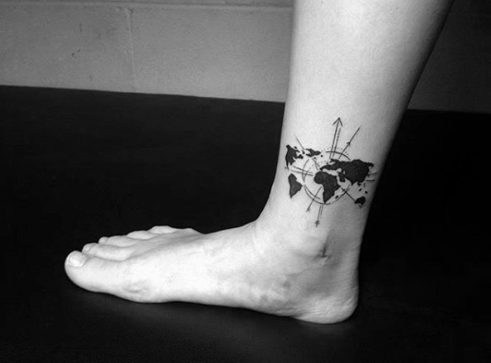 map of the world, decorated with circles and arrows, tattooed in black, on a person's ankle, meaningful tattoo ideas, freedom and travelling