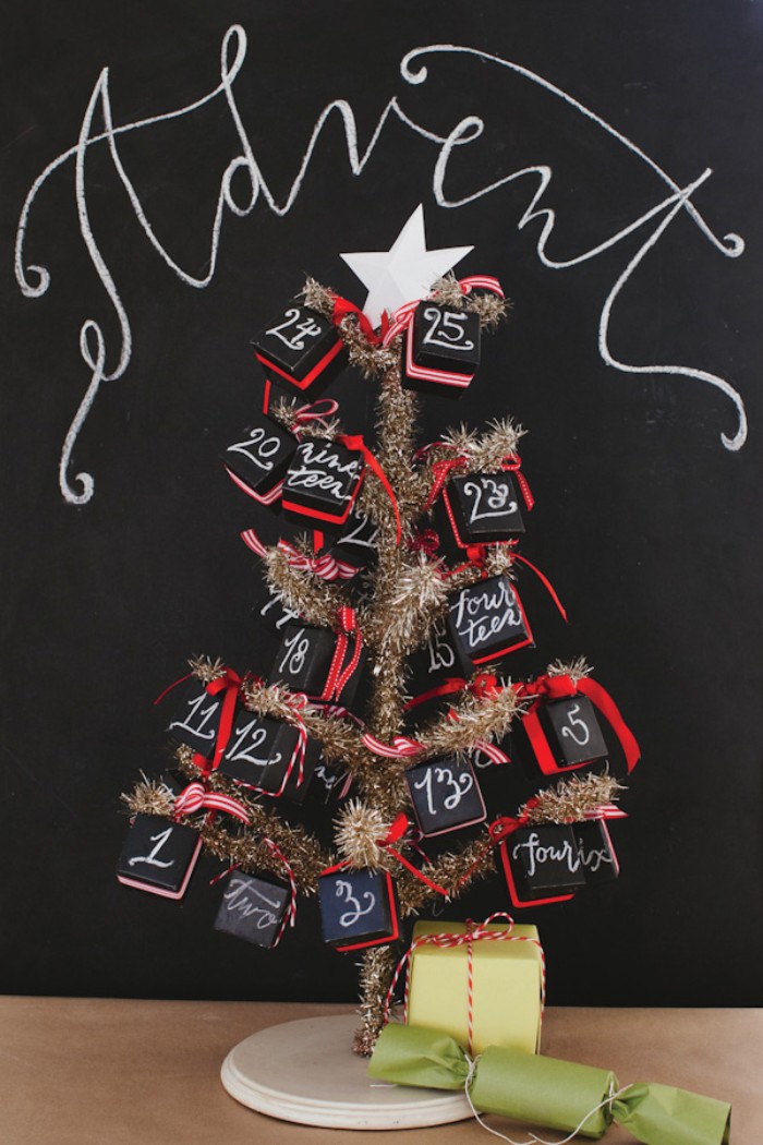 small faux christmas tree in gold, decorated with black cube-shaped boxes, featuring numbers written in white, and red bows, diy advent calendar