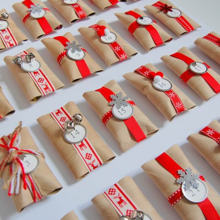 gift wraps made from toilet paper rolls, decorated with red and white patterned ribbon, yarn and plain red ribbon, with small round, numbered labels and bells, snowflake shapes and other decorations, advent calendar ideas, seen in close up