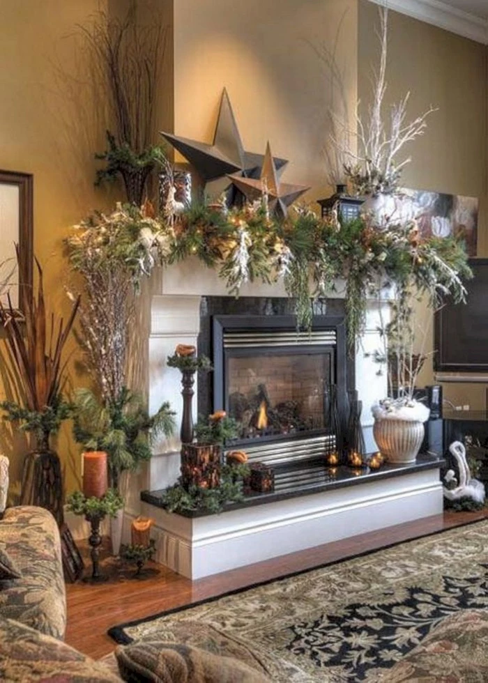 set of two beige star ornaments, one large and the other smaller, placed on a white mantel, decorated with a lush garland, made from pine branches, and other plants