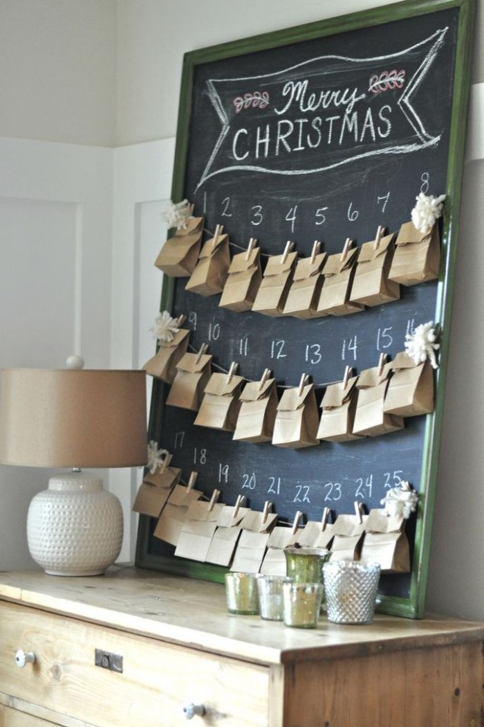 plain small brown paper bags, attached to three pieces of string, with wooden clothes pegs, the string is hanging on a framed blackboard, and there is a number from 1 to 25, written in white chalk above each bag