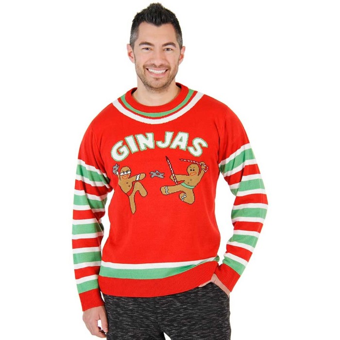 gingerbread men dressed like ninjas, on an orange-red cute ugly christmas sweater, with white and light green stripes, and the word ginjas, worn by a smiling man