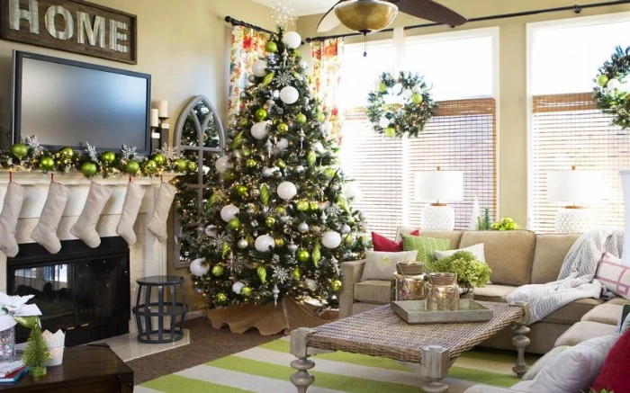 fireplace decor, with five white stockings, and a silver garland, featuring green baubles, christmas tree with similar ornaments, standing nearby