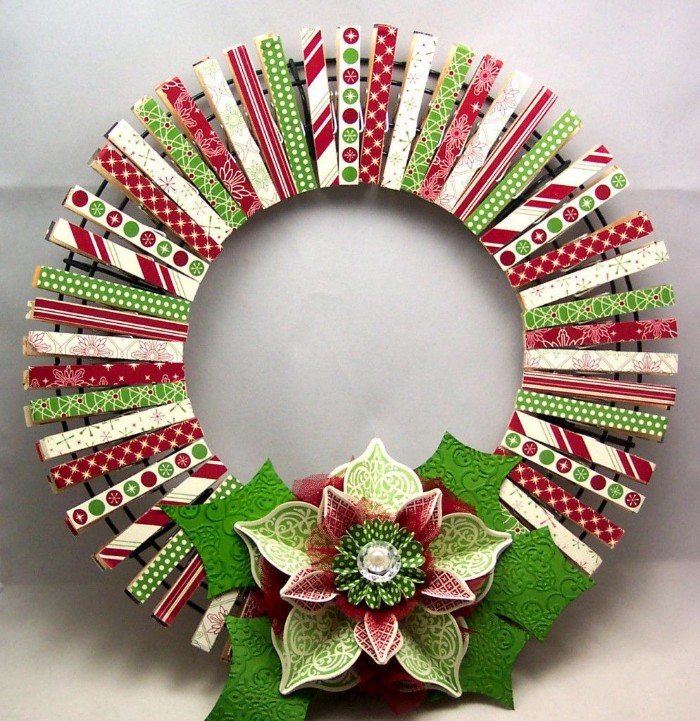 pegs made of wood, decorated with paper decoupage, featuring green and red, and white patterns, clipped onto a round metal frame, to form a wreath, decorated with a large paper flower, wreath ideas 