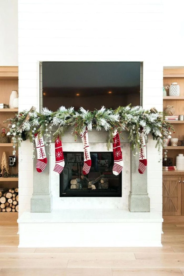 garland made from green, faux pine branches, decorating a christmas fireplace, with five and red stockings