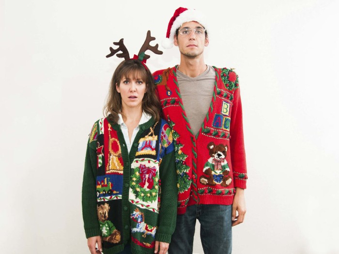 ugly sweater party, couple wearing festive cardigans, in dark green and red, decorated with multicolored motifs, featuring teddy bears, xmas wreaths and others