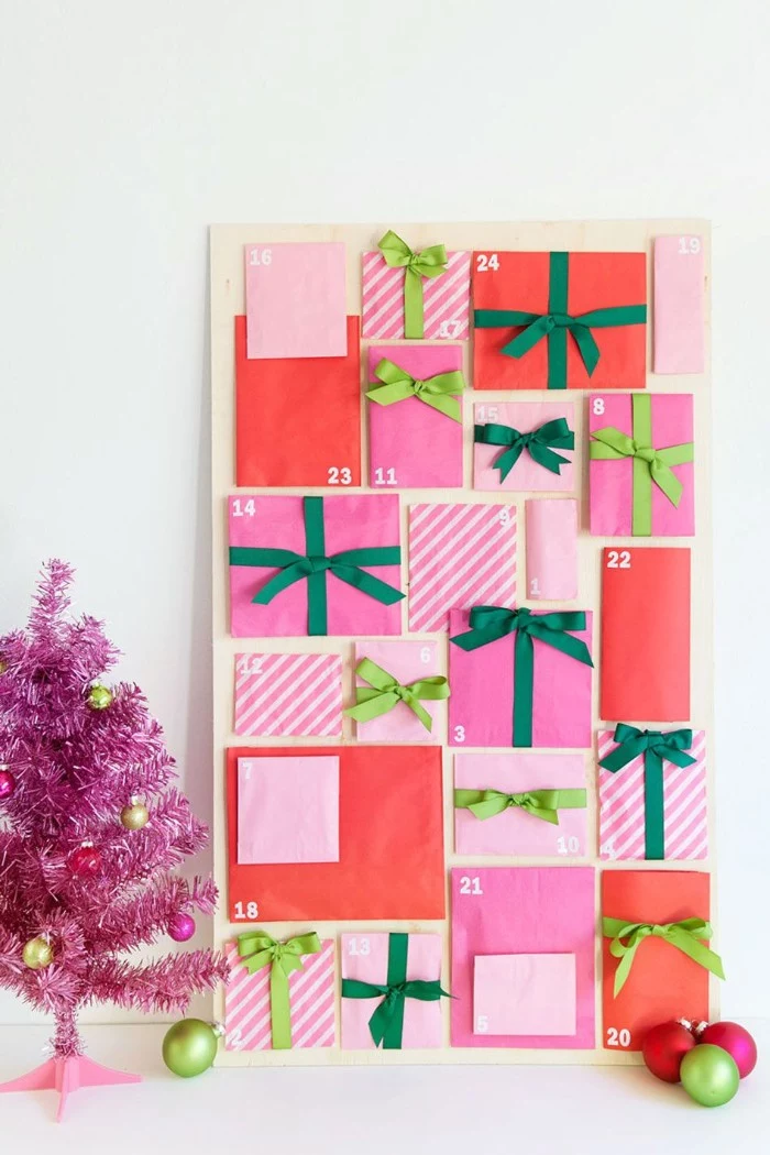 coral red and bubblegum pink envelopes, some with white stripes, in different sizes and shapes, decorated with light, and dark green ribbons, stuck to a rectangular board, fun advent calendars, each envelope has a small white number, from 1 to 24