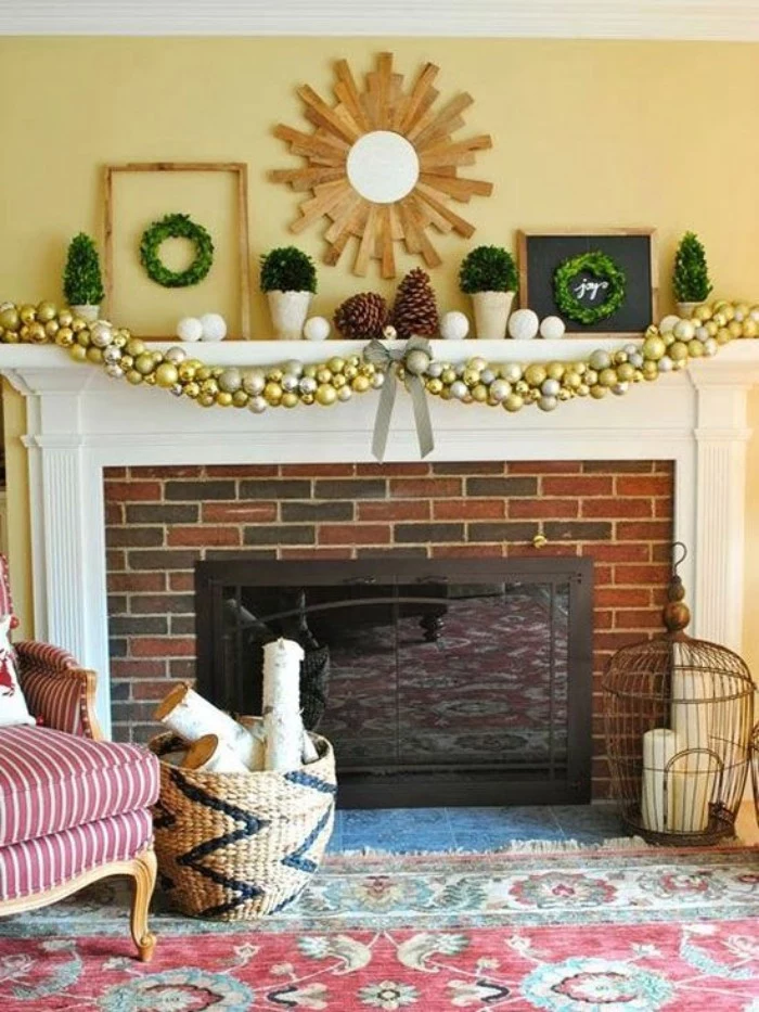 kilim rug in red, green and white, near a brick fireplace, decorated with a gold and silver garland, two gigantic pinecones, two small framed wreaths, white baubles and others