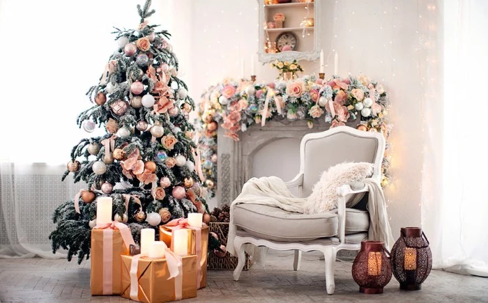 peach pink roses and baubles, decorating a white mantelpiece, and a christmas tree, inside a bright living room, christmas mantel ideas, presents and candles nearby