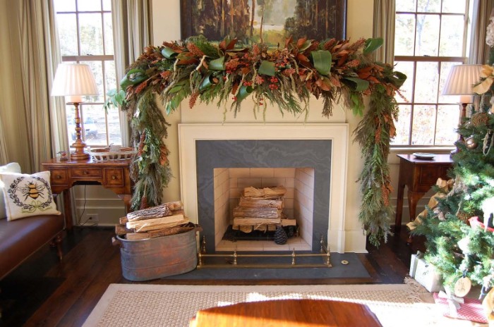 19th century style room, with a fireplace, displaying a lavish mantel decor, featuring a voluminous green garland, made of various branches and leaves