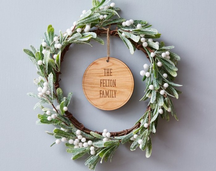 the felton family, etched on a round wooden tag, attached to wreath, made from mistletoe branches, christmas wreath images, green leaves and white berries, dusted with fake snow
